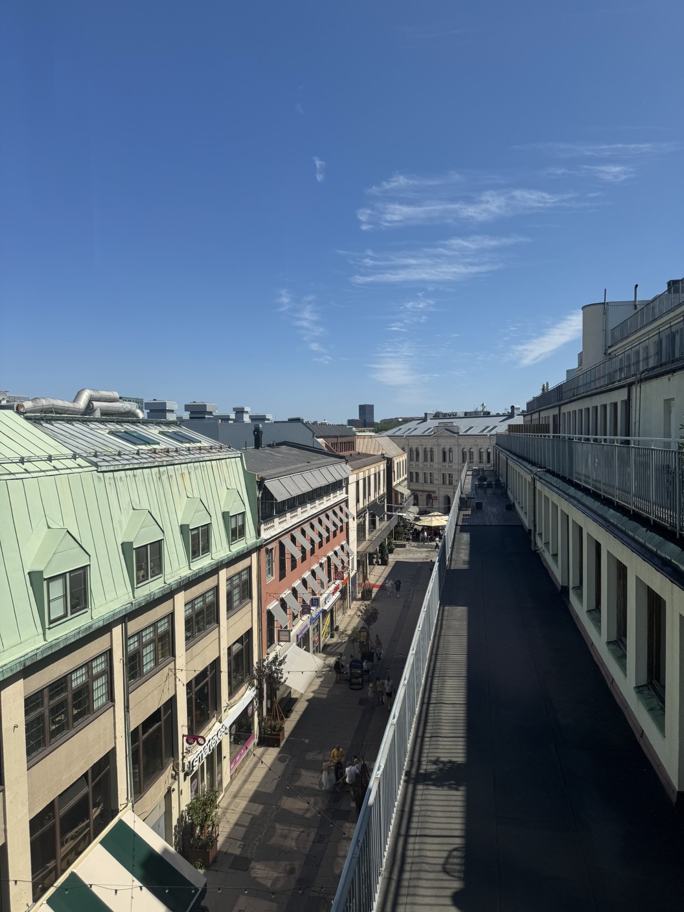 Utsikt från fönster över koppartak och gågata i Göteborg.